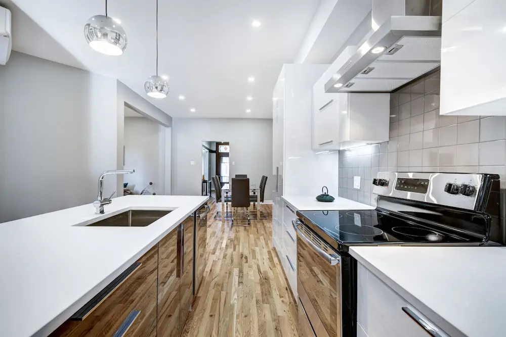 Moderne Küchenrenovierung mit weißen Fronten und Holzfußboden